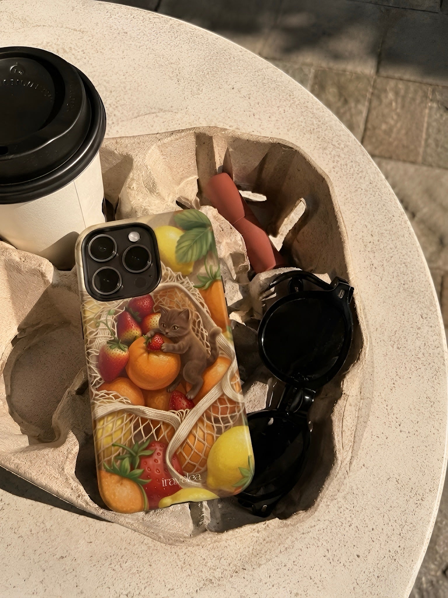 Phone case with lemon design on a stone surface with sunglasses and coffee.